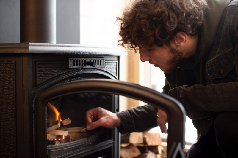 man lighting a fire in a wood burning stove, close up