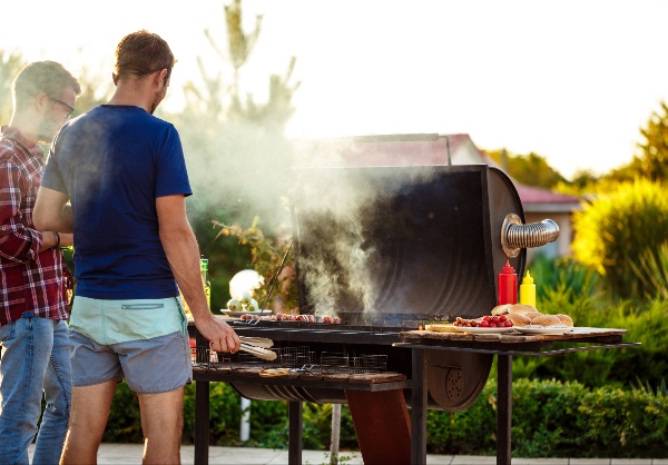 two men smoking food on a barbecue